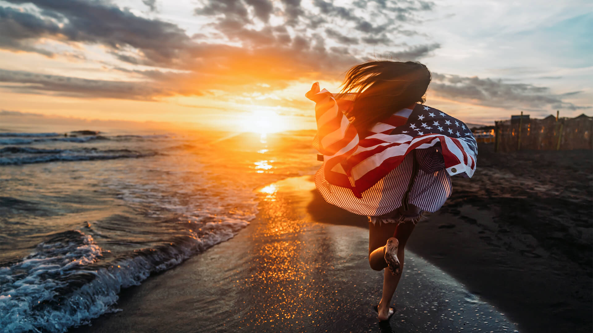 Girl running down the beach with an American Flag