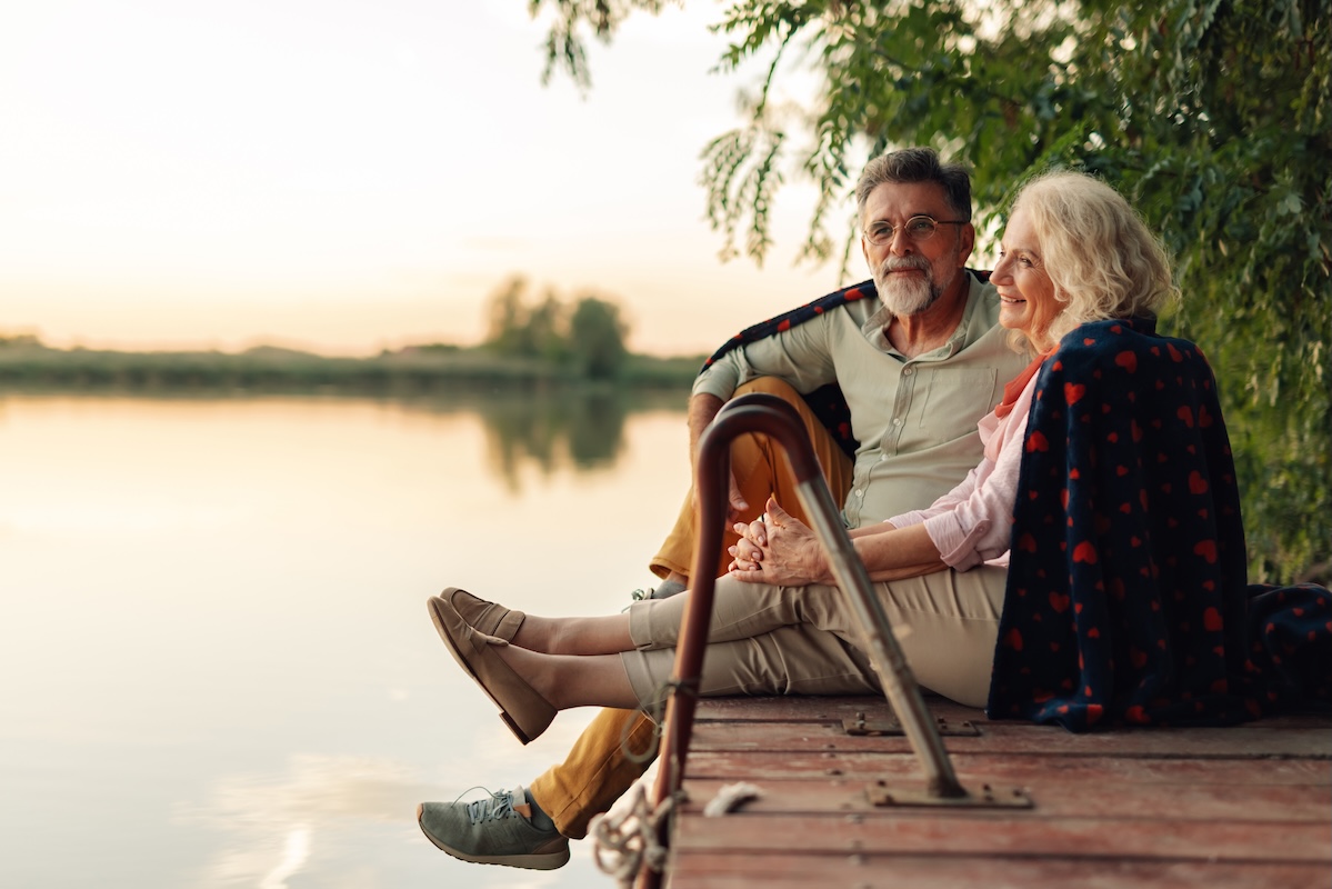 Business owners enjoying retirement by a lakeside dock after selling a company, representing post-exit planning, retirement income strategies, wealth management, and life after a business sale with guidance from iWealth.